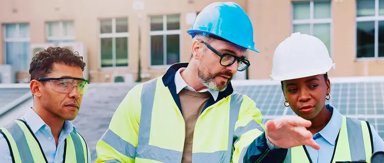 A person in a helmet and apron talks on a cell phone.