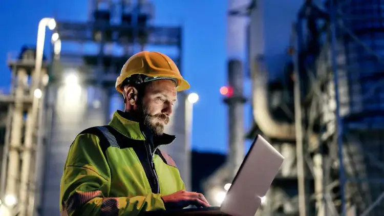 A person in a yellow vest using a laptop computer.