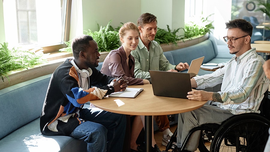 A group of people sitting around a table with laptops.