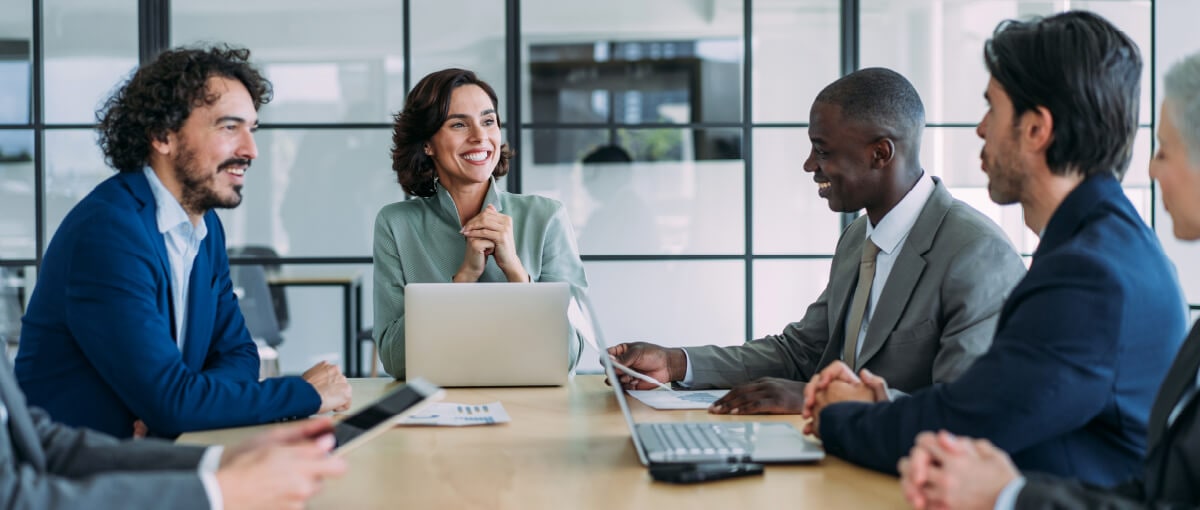 A person and person sitting at a table with laptops.