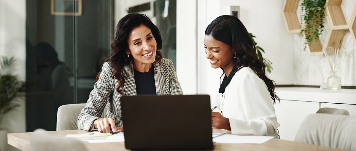 Two people sitting at a table with a laptop.